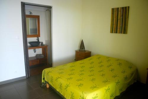 a bedroom with a yellow bed and a mirror at La case Tori in Saint-Leu