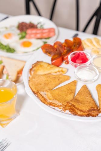 a white plate with breakfast foods on a table at Azamat Hotel in Astana