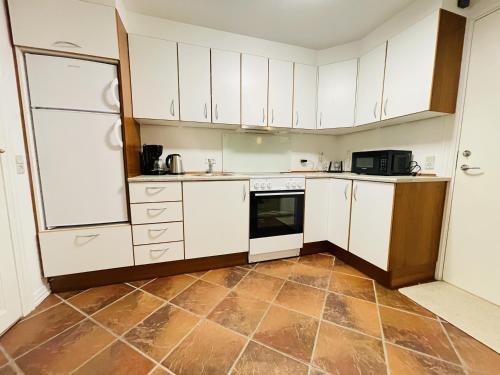 cocina con armarios blancos y suelo de baldosa en aday - Cozy central 1 bedroom apartment, en Frederikshavn