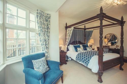 1 dormitorio con cama con dosel y silla azul en Findon Manor Hotel, en Worthing