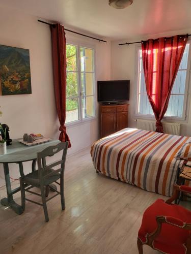 um quarto com uma cama, uma mesa e janelas em Le clos Fleury Cluny em Cluny