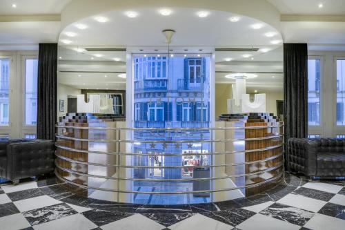 a lobby with a bar with blue walls and chairs at Hotel Larios Málaga in Málaga
