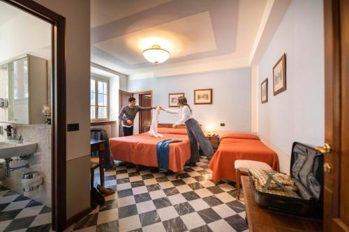 a man and woman jumping on beds in a hotel room at Park Hotel Regina - with air-condition and pool in Bagni di Lucca