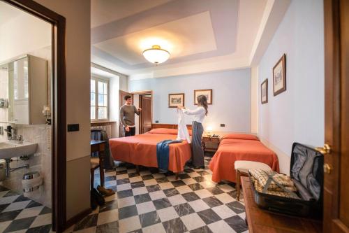 a woman standing in a hotel room with two beds at Park Hotel Regina - with air-condition and pool in Bagni di Lucca