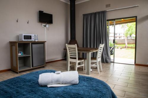 Pokój z łóżkiem i stołem z kuchenką mikrofalową w obiekcie Opstal Guestfarm w mieście Potchefstroom