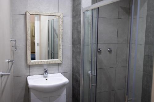 a bathroom with a sink and a shower with a mirror at Opstal Guestfarm in Potchefstroom