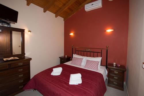 a bedroom with a bed with a red wall at Erikousa Villas by CorfuEscapes in Ereikoússa