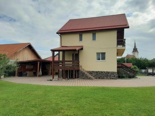 una casa con techo rojo y un campo de hierba en Casa Costache, en Brasov