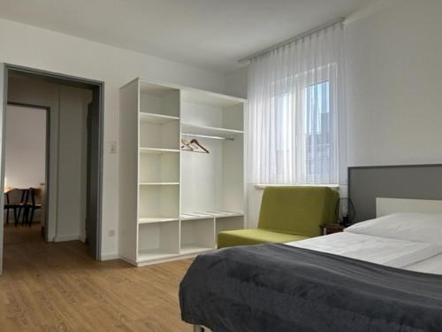ein Schlafzimmer mit einem Bett, einem Stuhl und einem Fenster in der Unterkunft Aparthotel Gartenstadt in Bamberg