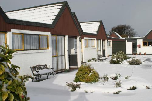 a house with a bench in the snow at Bavarian Motel in Invercargill