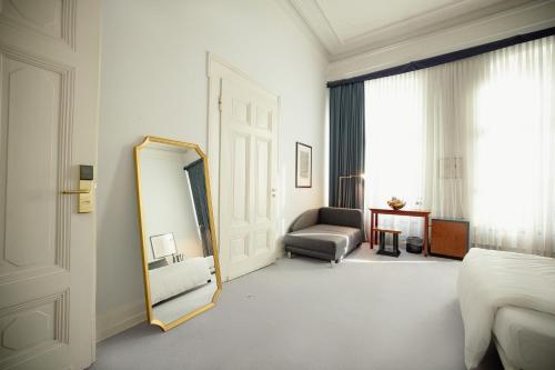 Habitación con espejo, cama y silla en Domicil Hotel Bonn en Bonn