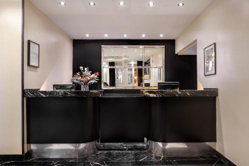 a hotel lobby with a black counter with flowers at Hotel Larios Málaga in Málaga