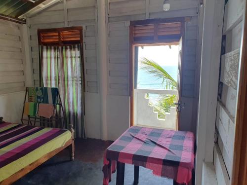 Cette chambre comprend un lit, une fenêtre et une table. dans l'établissement Chandi Gaya Beach Guesthouse, à Tangalle