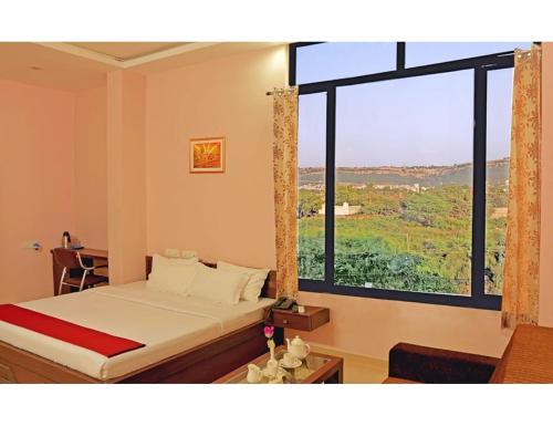 a bedroom with a bed and a large window at Hotel Shivam Fort View, Chittorgarh in Chittaurgarh