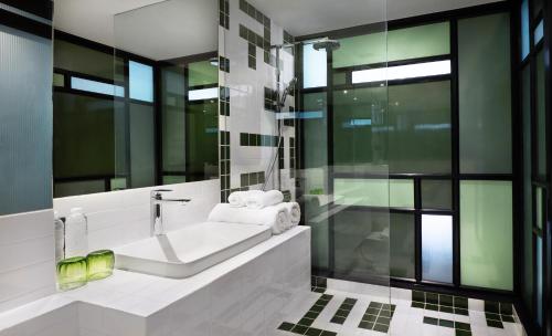 een badkamer met een bad en een glazen douche bij Hotel Sapin in Pom Prap