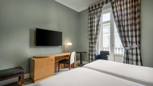 a hotel room with a desk and a television at Hotel Larios Málaga in Málaga