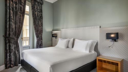 a large white bed in a room with a window at Hotel Larios Málaga in Málaga