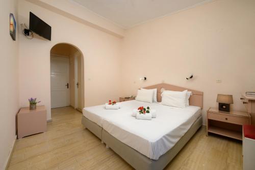 Un dormitorio con una gran cama blanca con flores. en Siora Leni Hotel en Benitses