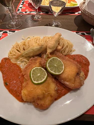 a plate of food with chicken pasta and lime slices at Hotel Fassbind Beausite in Beatenberg