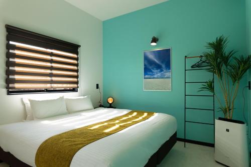 a bedroom with a large bed and a blue wall at クリスタルパーク久松 in Miyako Island