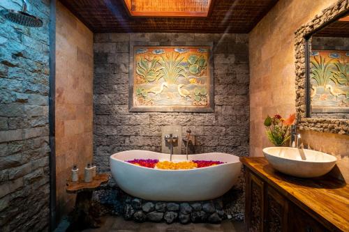 a bathroom with a bath tub and a sink at Bunut Garden Luxury Private Villa in Ubud