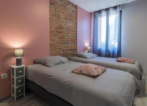 two beds in a room with a brick wall at Domaine le Caprougeat in Daux
