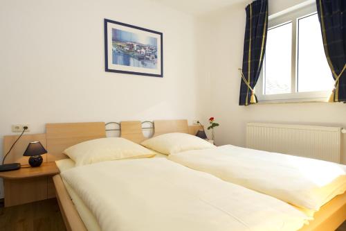 Haus Südstrand في غورين: غرفة نوم بسرير كبير مع شراشف بيضاء