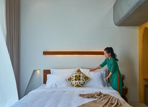 a young girl standing on top of a bed at Barbados Cherry Villa in Hoi An