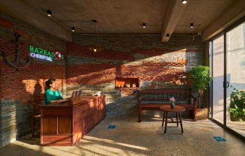 a woman sitting at a desk in a room with a brick wall at Barbados Cherry Villa in Hoi An