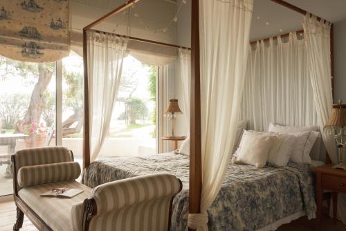 a bedroom with a canopy bed and a chair at Villa Pueblo in Nafplio