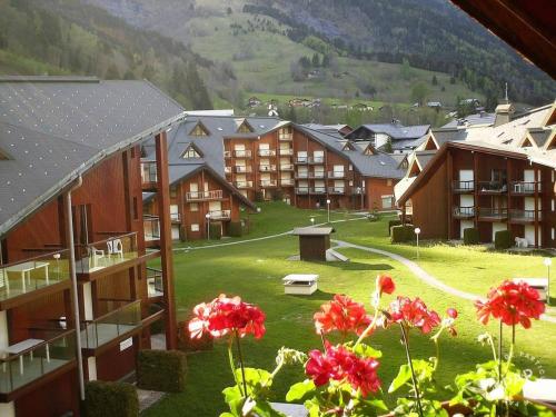 grupa budynków z czerwonymi kwiatami na pierwszym planie w obiekcie Un havre de paix aux pieds des chemins de montagne w mieście Contamines-Montjoie