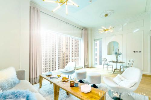Elle comprend un salon doté d'un mobilier blanc et d'une grande fenêtre. dans l'établissement LUX Marina Promenade Penthouse Suite, à Dubaï
