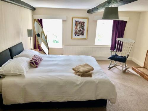 - une chambre avec un grand lit blanc et une chaise dans l'établissement Cosy Farmhouse Escape in Monmouthshire, à Wolves Newton