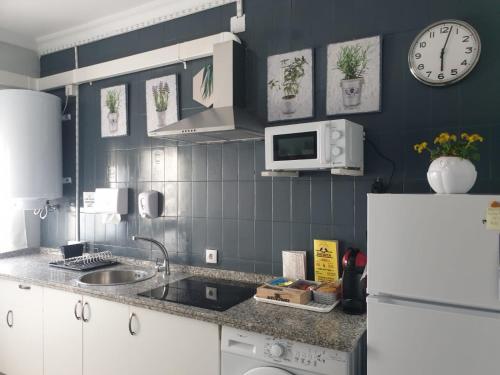 a kitchen with a sink and a clock on the wall at Apartamento Ana Maria in San Juan del Puerto