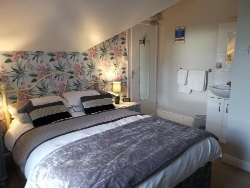 a bedroom with a large bed with a floral wallpaper at Brooklands Guest House in Bowness-on-Windermere