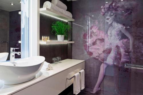 uma casa de banho com lavatório e uma mulher no chuveiro em Renaissance Wien Hotel em Viena