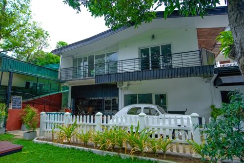 a white house with a white fence and a white car at Water Front Hotel Kandy in Kandy