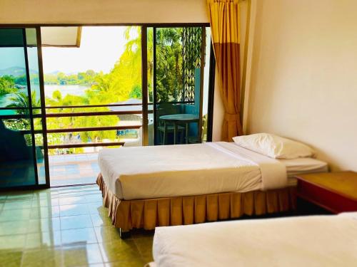 a hotel room with two beds and a balcony at Duenshine Resort in Kanchanaburi