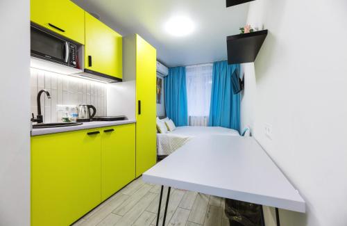 a small kitchen with yellow cabinets and a white table at Апартаменти на Відрадному від MYFREEDOM in Kyiv