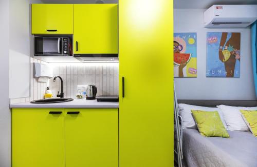 a kitchen with yellow cabinets and a bed in a room at MYFREEDOM Апартаменти метро Святошин in Kyiv
