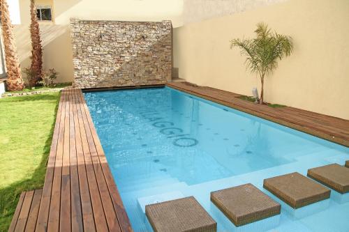 uma piscina num quintal com um deque de madeira em Villaggio Hotel Boutique em Mendoza