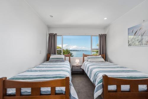 two beds in a room with a view of the ocean at Lakeside Terrace - Taupo Holiday Home in Taupo