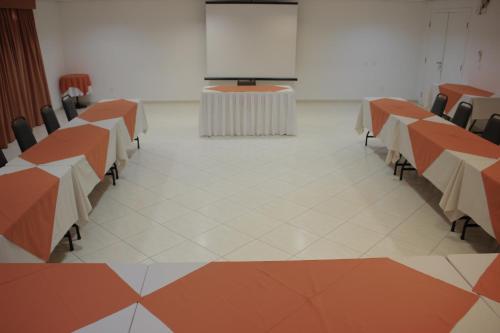 a conference room with tables and chairs and a screen at Harbor Self Graciosa Hotel in Quatro Barras