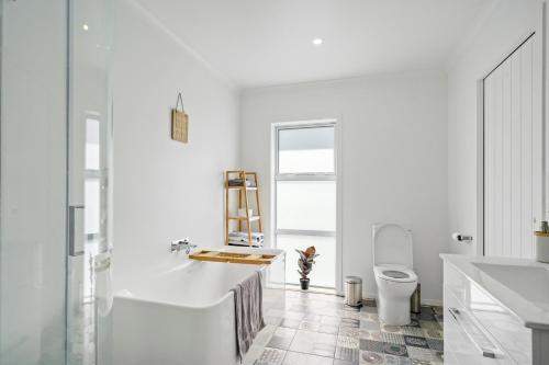 a white bathroom with a tub and a toilet at Contemporary Comfort - Masterton Holiday Home in Masterton