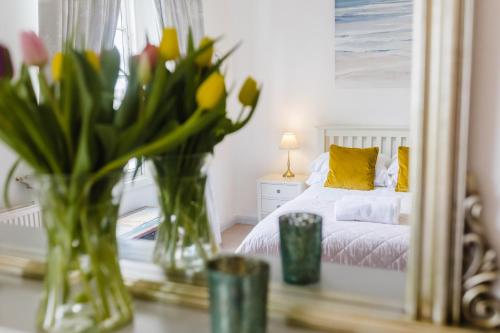 1 dormitorio con flores en jarrones sobre una mesa en May Tree Cottage Manorbier 5 mins from the beach Sleeps 4 en Manorbier