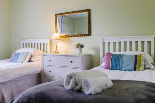 a bedroom with two beds with a mirror and a dresser at May Tree Cottage Manorbier 5 mins from the beach Sleeps 4 in Manorbier