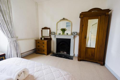 a bedroom with a bed and a mirror and a fireplace at May Tree Cottage Manorbier 5 mins from the beach Sleeps 4 in Manorbier