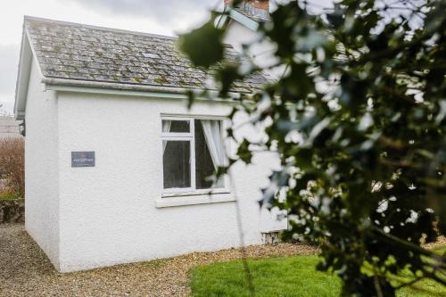 a white house with a window in a yard at May Tree Cottage Manorbier 5 mins from the beach Sleeps 4 in Manorbier
