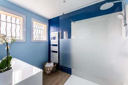 baño con paredes azules y cabina de ducha de cristal en Le Domaine des pins - Maison 2 Chambres vue mer, en Le Tréport