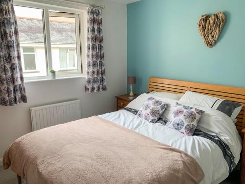 een slaapkamer met een bed met kussens en een raam bij Corner Cottage in Combe Martin